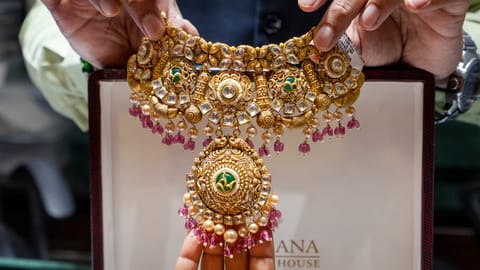 A salesperson shows a necklace to a customer at a jewellery shop, in Amrisar, Punjab, Wednesday, May 13, 2026. Jewellers and industry leaders on Wednesday said the hike in import duty on gold and silver could impact jewellery volumes in the short term, though demand is expected to remain resilient due to the yellow metal's enduring cultural and investment appeal in India