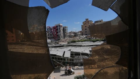 Buildings damaged by Israeli strikes are seen through shattered glass from the Jabal Amel Hospital in the southern port city of Tyre, Lebanon