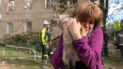 A woman holds her cat after it being found during search and rescue works in the damaged residential building following Russia's missile attack
