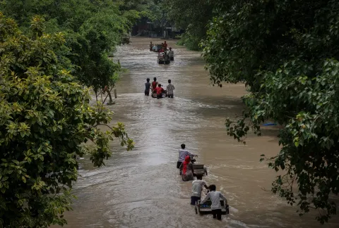 Residents carry their belongings on rickshaws through a street flooded with the rising water level of river Yamuna after heavy monsoon rains in New Delhi, India, July 12,