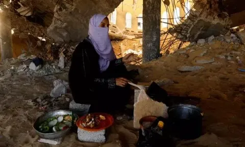 A woman cooks in a destroyed mosque, amid shortages of food supplies and fuel in Khan Younis (Photo: Reuters)
