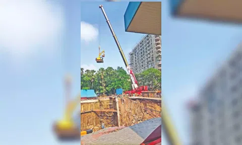 An all-terrain telescopic crane lowering an earthmover into the pit.