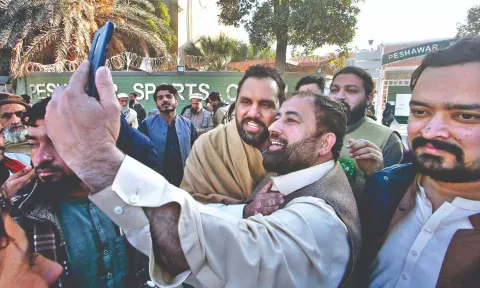 A candidate backed by Imran’s party poses for a selfie with supporters following his victory.