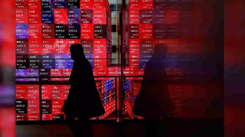 A visitor walks past Japan's Nikkei stock prices quotation board inside a building in Tokyo (Photo/Reuters)