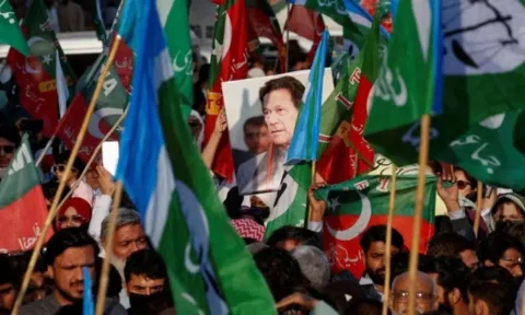 A portrait of the former Prime Minister Imran Khan is seen amid flags of Pakistan Tehreek-e-Insaf (PTI)