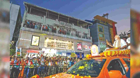 Modi showing the symbol Lotus to people during roadshow in city