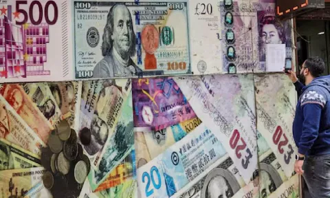A man takes a photograph of exchange rates in front of an exchange point, displaying images of different currencies, in Cairo (Reuters)
