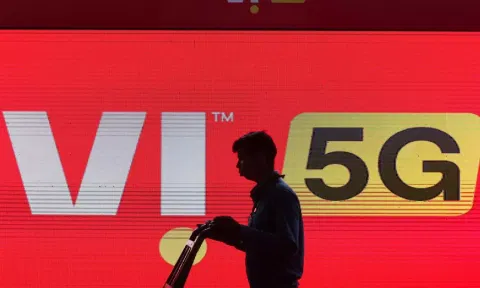 A man walks across the LED display board showing the logo of Vodafone-Idea (Reuters)