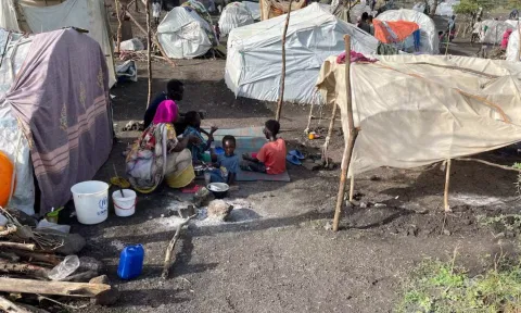 People sit by makeshift shelters near Awlala Camp (Reuters)