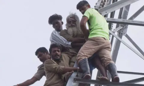 Auto drivers and fire fighters bringing down protesting Rajendran from high-tension power tower in Tiruchy on Wednesday