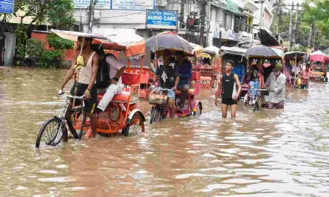&nbsp;Rickshaw pullers carry passengers through a flooded street after incessant rains, in Guwahati (PTI)