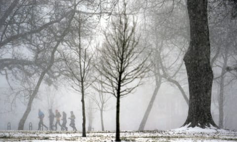A group of people jog in the distance as heavy snow falls Sunday (AP)