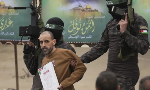 Israeli captive Eli Sharabi, who had been held hostage by Hamas in Gaza since Oct 7, 2023, is escorted by Hamas fighters before being handed over to the Red Cross in Deir al-Balah