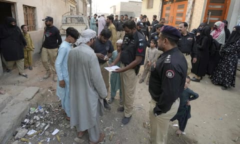 A Police officer checks documents of a resident during a search operation against illegal immigrants, at a neighbourhood of Karachi, Pakistan, Nov 2, 2023 (AP)&nbsp;