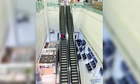 A passenger walking down the steps of a static escalator
