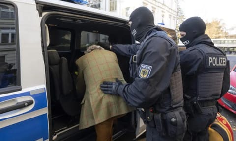 &nbsp;Masked police officers lead the arrested suspect Heinrich XIII Prince Reuss, left, to a police vehicle during a raid against so-called ‘Reich citizens’ in Frankfurt, Germany (AP)