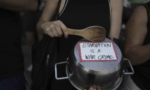 An Israeli activist bangs a pot with a wooden spoon to protest the starvation of Palestinian civilians in the Gaza Strip, outside the U.S. Embassy branch office in tel Aviv, Israel (AP)&nbsp;