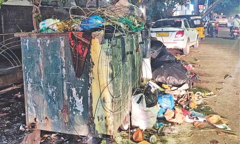 Dumped large polythene bags of refuse near trash bins on the busy stretch