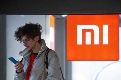 A man uses his smartphone next to the Xiaomi brand's store
