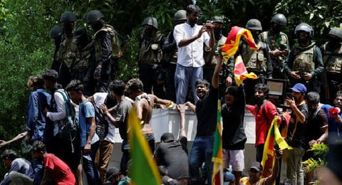Demonstrators stand on the wall of Sri Lanka's Prime Minister Ranil Wickremesinghe's office premises