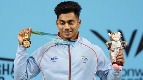 Gold Medallist India's Achinta Sheuli celebrates on the podium during the medal ceremony.