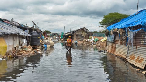 A woman walks through a waterlogged Munnekolala slum area
