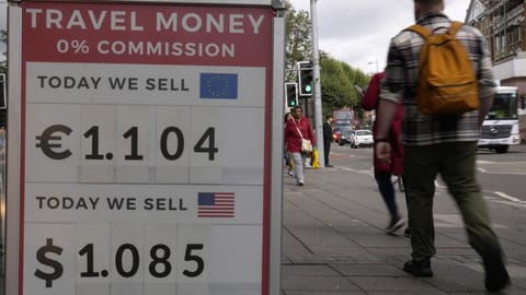 Pedestrians pass a currency exchange sign outside a shop in London.