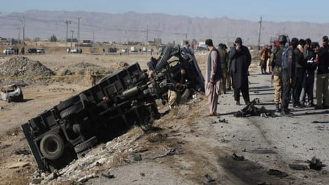 Police officers in civilian clothes survey the aftermath of a suicide bomb blast on a police patrol