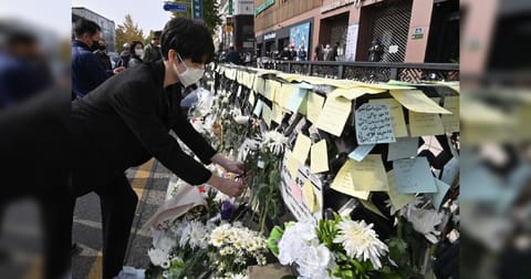 A mourner lays flowers at a makeshift memorial for the victims of the deadly Halloween crowd surge