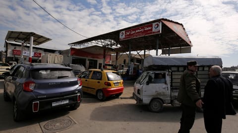 Cars stand in line at a gasoline station as they wait to fuel up in Aleppo