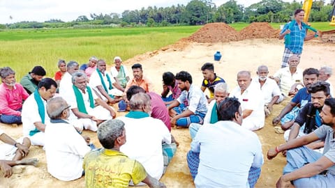Farmers on hunger strike at the venue; (below) soil intended for road project being spread over paddy fields