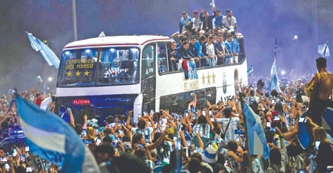 Football fans surround the bus carrying the newly crowned world champion Argentina in Buenos Aires on Tuesday