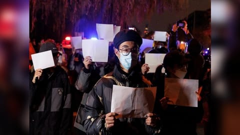 People gather for a vigil and hold white sheets of paper in protest over Covid-19 curbs