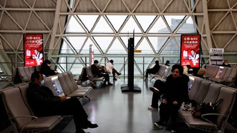 Travellers wait to board their plane at Chengdu Shuangliu International Airport amid a wave of the coronavirus disease infections