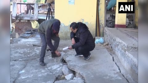 Officials inspect land subsidence by placing a gauge over cracks in subsidence affected area of Joshimath