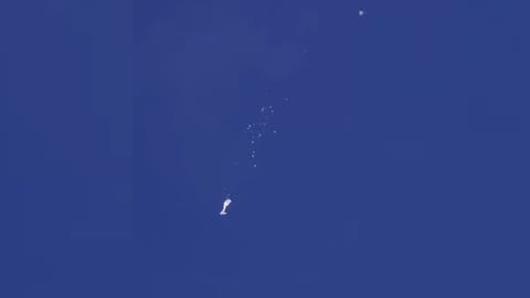 The remnants of a large balloon descend after it was struck by a missile