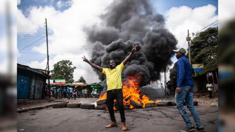 Protesters react next to a burning barricade during a mass rally called by the opposition leader Raila Odinga over the high cost of living, in Kibera Slum, Nairobi, Kenya