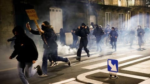 Protesters run amid clashes as they attend a demonstration on the day the National Assembly debates and votes on two motions of no-confidence against the French government