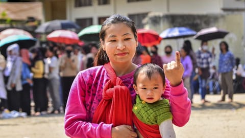Woman carrying a kid shows her ink-marked finger after casting her vote for the Nagaland Assembly elections, at a polling station in Dimapur, Monday, Feb. 27, 2023