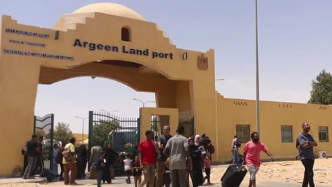 Evacuees carry their luggages as they cross into Egypt through the Argeen land port