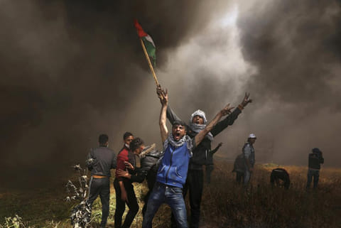 Palestinian demonstrators shout during clashes with Israeli troops at a protest