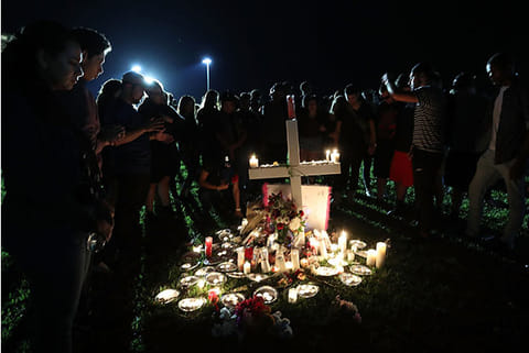 Students, friends, and family gather to pray during a candlelight vigil