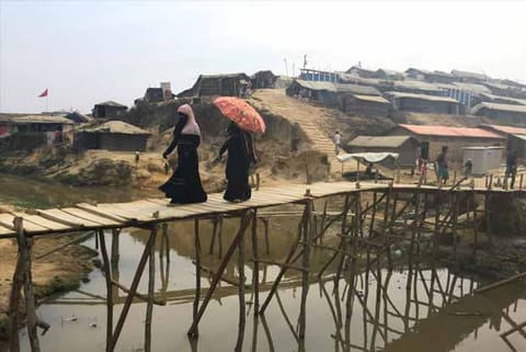 Women walk across a bamboo bridge in the Kutupalong camp for Rohingya refugees in southern Banglades