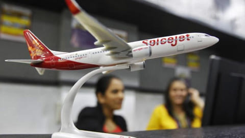 Employees work inside a travel agency office besides a model of a SpiceJet aircraft