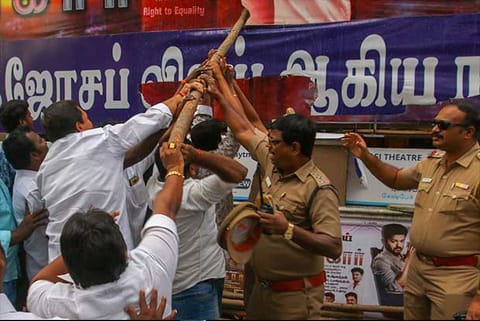 A police officer tries to stop protesters from damaging banners of the film