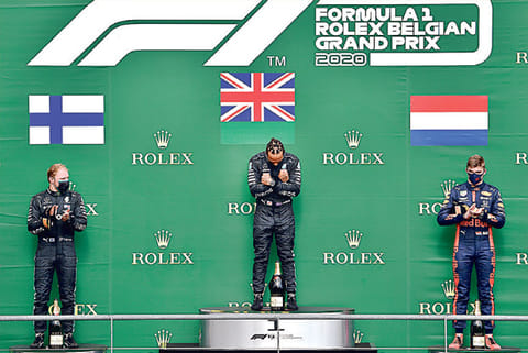 Lewis Hamilton (centre) gestures on the podium