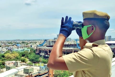A policeman with binoculars on the terrace of suburban train terminal at Central