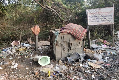 Despite a warning board that says not to dump waste, garbage, including a toilet seat, is discarded