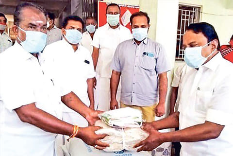 Minister KA Sengottaiyan distributing free rice to people in Erode on Thursday