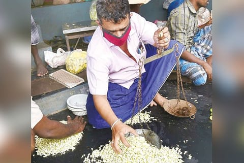 A trader weighing jasmine at Mattuthavani flower market in Madurai on Sunday.